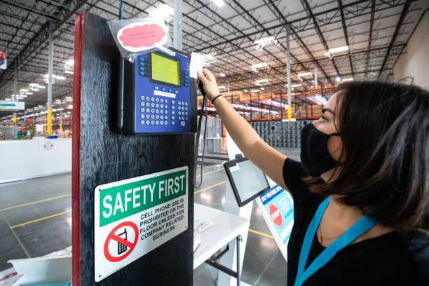 a person in a mask swipes a card into a terminal in a warehouse