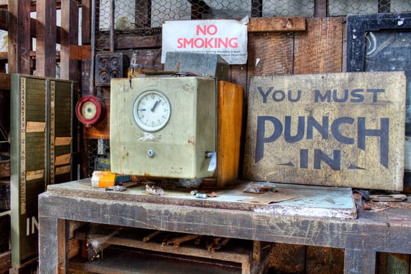 an old fashioned punch clock on top of a work table next to a sign that reads "you must punch in"