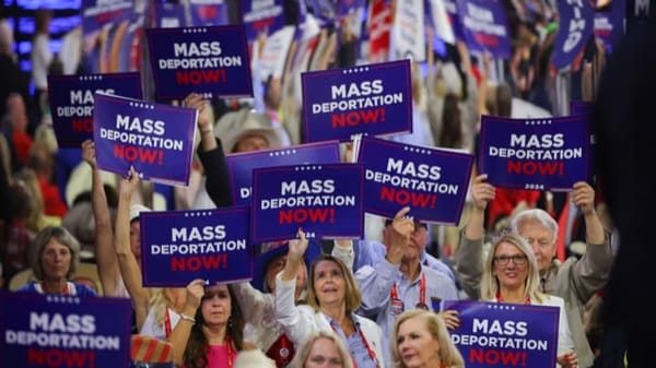 a crowd of white delegates at the RNC holding up signs that read Mass Deportation Now!
